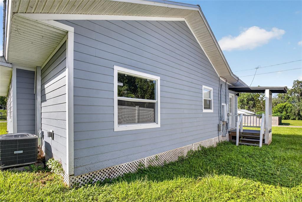 The exterior of a light blue house features horizontal siding, a window, and a small porch — 4104 ORANGE AVENUE SE, HIGHLAND CITY, FL