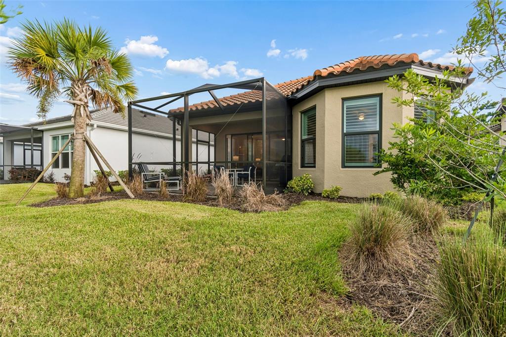 A tan house with a screened-in patio, tile roof, and palm tree in the yard — 4618 ROSATTI ROAD, WESLEY CHAPEL, FL