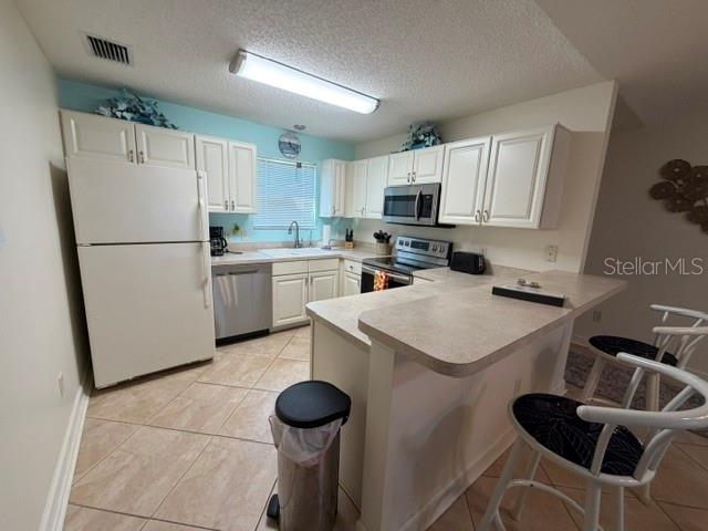 A kitchen features white cabinets, a white refrigerator, a breakfast bar, and tile flooring — 1413 BLUEBERRY WAY, THE VILLAGES, FL