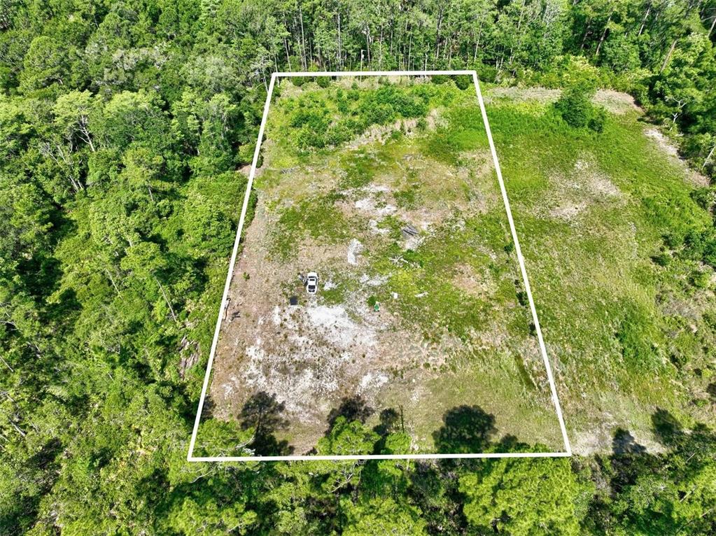 An aerial view shows a rectangular, cleared plot of land surrounded by dense forest — KINGS ESTATE ROAD, ST AUGUSTINE, FL