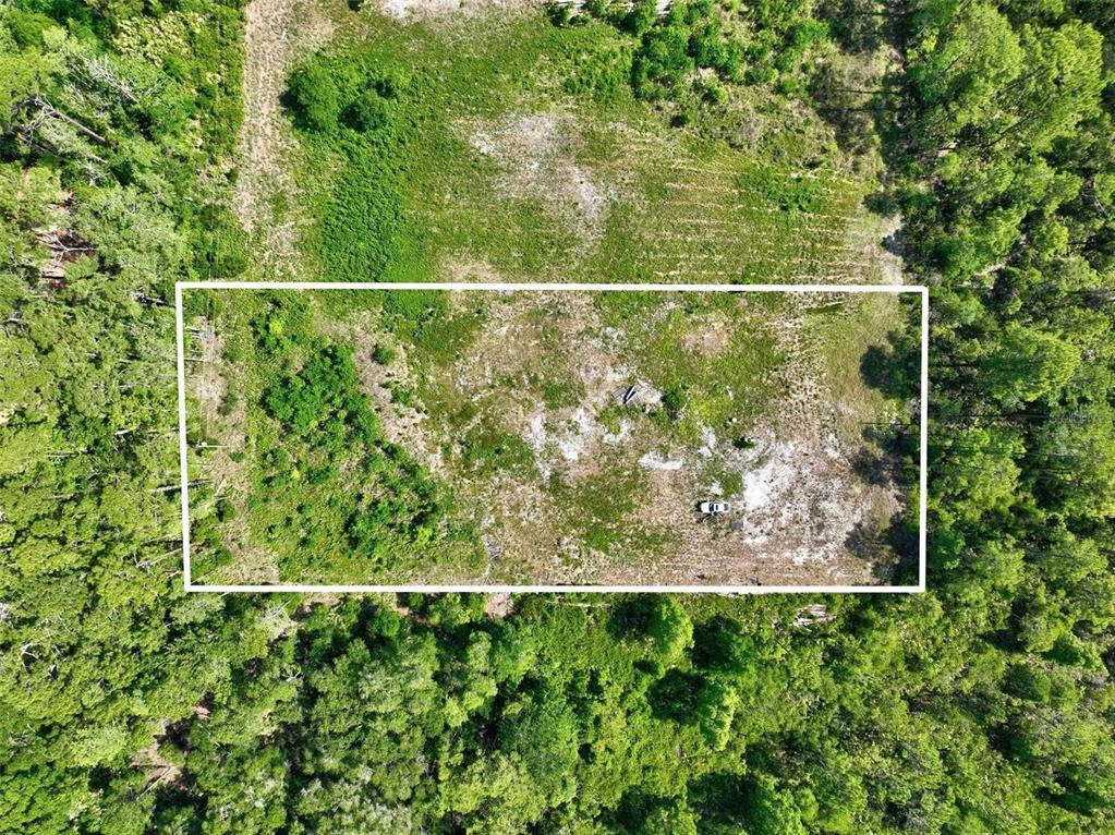 An aerial view shows a rectangular plot of cleared land surrounded by dense green forest — KINGS ESTATE ROAD, ST AUGUSTINE, FL