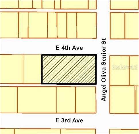 A vacant, fenced-in paved lot sits adjacent to a building under a blue sky — 1715 E 4TH AVENUE, TAMPA, FL
