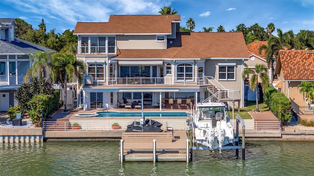 A two-story beige house with a paved driveway, palm trees, and a multi-car garage — 5918 SKIMMER POINT BOULEVARD S, GULFPORT, FL
