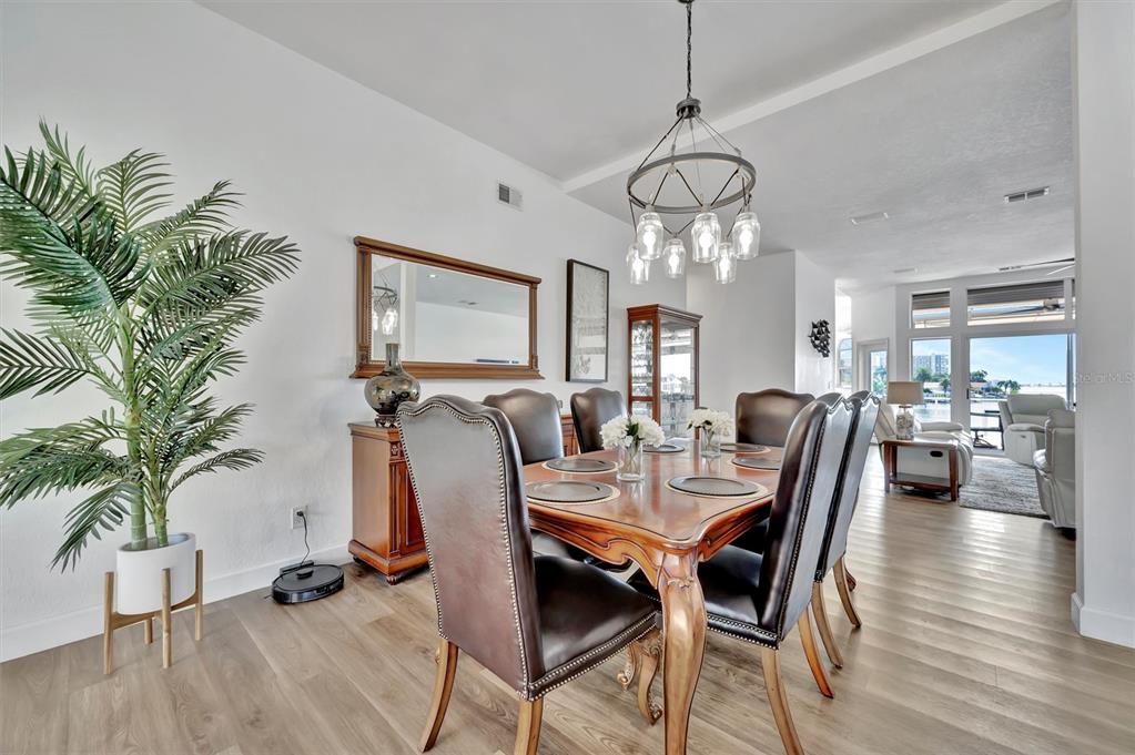 A dining area features a marble-topped table, wooden chairs, and large windows overlooking the water — 5918 SKIMMER POINT BOULEVARD S, GULFPORT, FL
