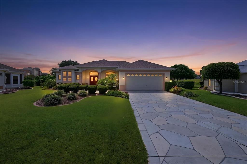 A single-story house with a stone driveway and a two-car garage at sunset — 1722 ENRIQUE DRIVE, THE VILLAGES, FL