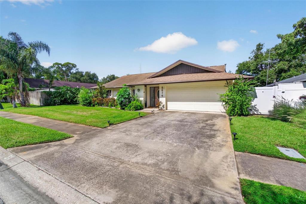 A single-story house with a two-car garage, concrete driveway, and a grassy front yard — 5674 BAY PINES LAKES BOULEVARD, ST PETERSBURG, FL