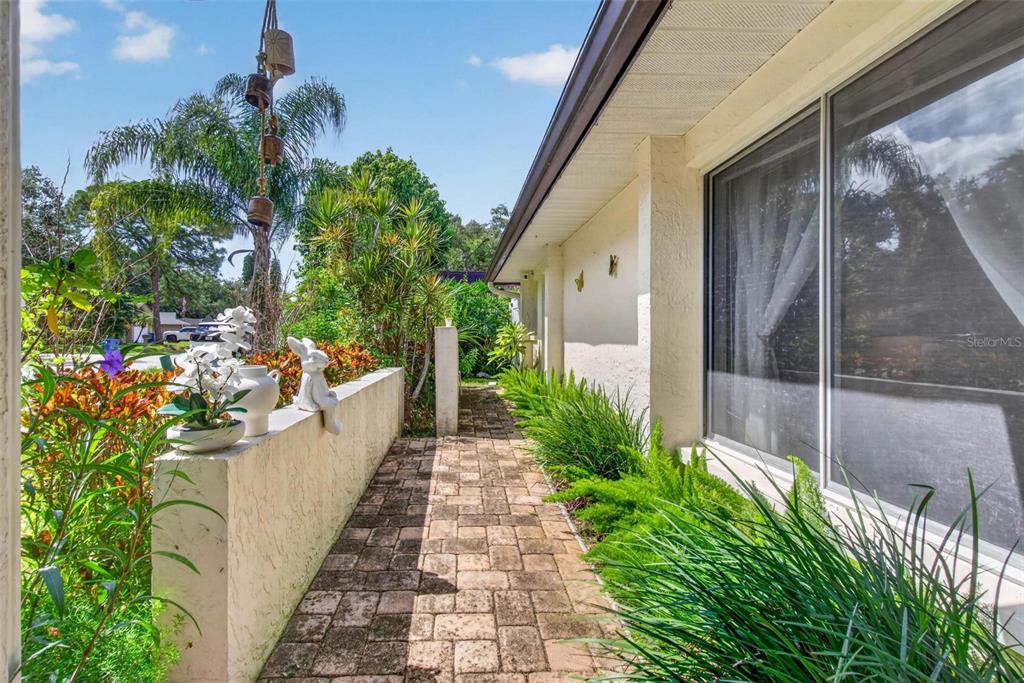 A paved walkway leads along the side of a house past a low garden wall — 5674 BAY PINES LAKES BOULEVARD, ST PETERSBURG, FL