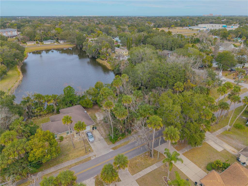 An aerial view of a house with a brown roof situated next to a pond — ENTERPRISE AVENUE, NEW SMYRNA BEACH, FL
