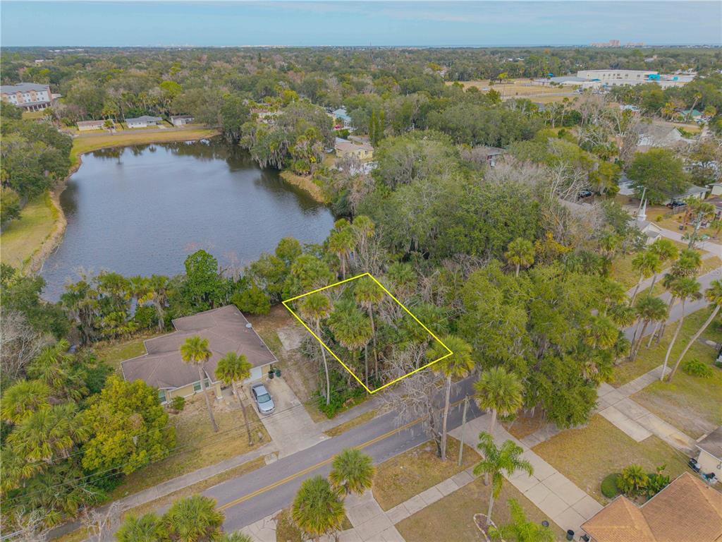 An aerial view shows a vacant, tree-covered lot outlined in yellow next to a house — ENTERPRISE AVENUE, NEW SMYRNA BEACH, FL