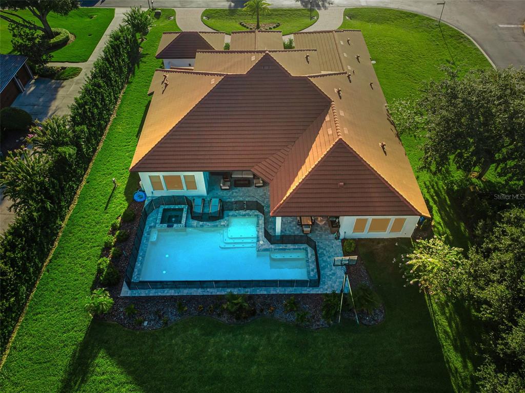An aerial view of a house with a tiled roof, swimming pool, and surrounding lawn — 1422 OAK MEADOW POINT, NEW PORT RICHEY, FL