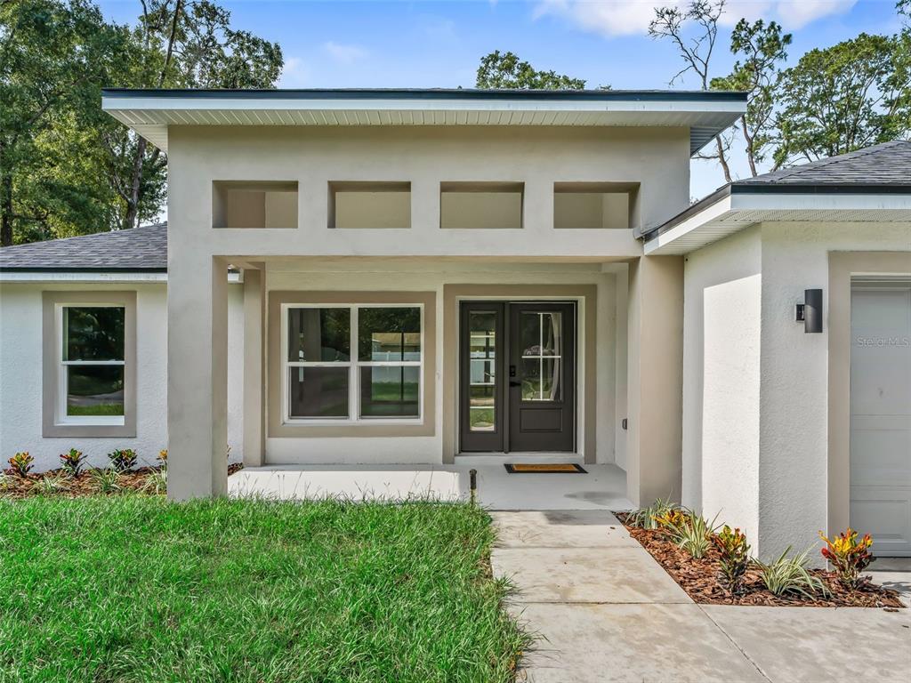 The exterior of a single-story house features a covered entryway, double front doors, and landscaping — 5386 NW 54TH PLACE, OCALA, FL