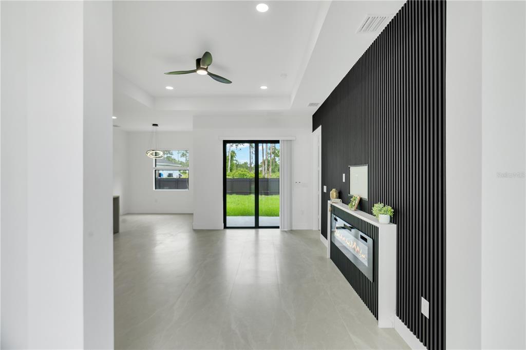 A living room features a black slatted accent wall, a fireplace, and sliding glass doors — 1047 MERRY STREET E, LEHIGH ACRES, FL
