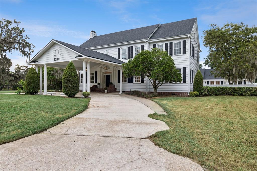 A two-story white house with black shutters and a large covered front porch entrance — 5240 ALLEMAN DRIVE, ORLANDO, FL
