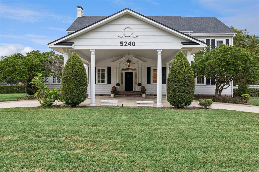 A white house exterior features a black front door, brick steps, and two white columns — 5240 ALLEMAN DRIVE, ORLANDO, FL