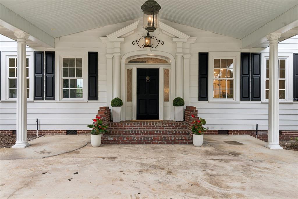 A white house exterior features a black front door, brick steps, and two white columns — 5240 ALLEMAN DRIVE, ORLANDO, FL