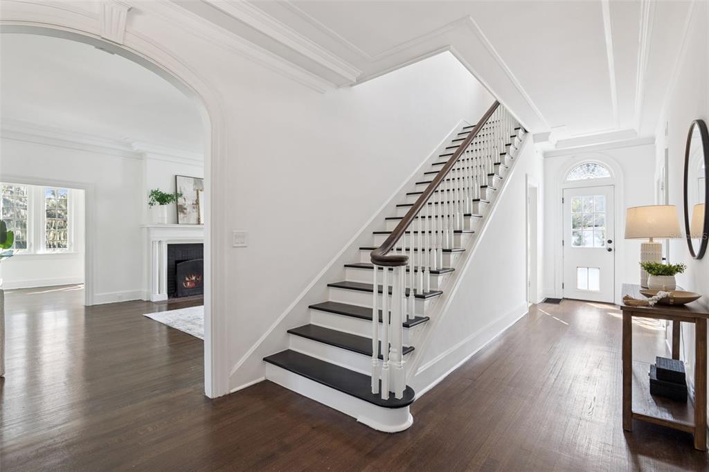 A bright foyer features a dark wood staircase, hardwood floors, and an arched entryway — 5240 ALLEMAN DRIVE, ORLANDO, FL