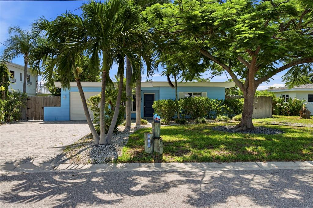 A light blue single-story house with a paved driveway, palm trees, and a large tree — 403 NORMANDY ROAD, MADEIRA BEACH, FL