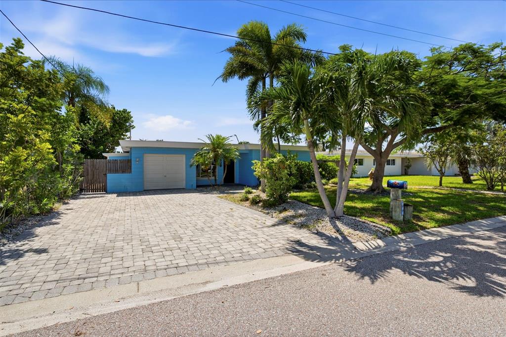 A blue single-story house features a paved driveway, a garage, and several palm trees — 403 NORMANDY ROAD, MADEIRA BEACH, FL