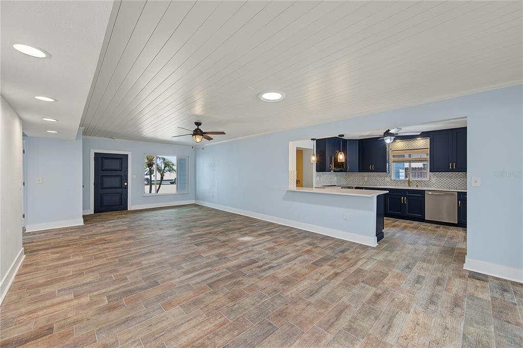 An open-concept living area features light blue walls, wood-look tile flooring, and a navy kitchen — 403 NORMANDY ROAD, MADEIRA BEACH, FL