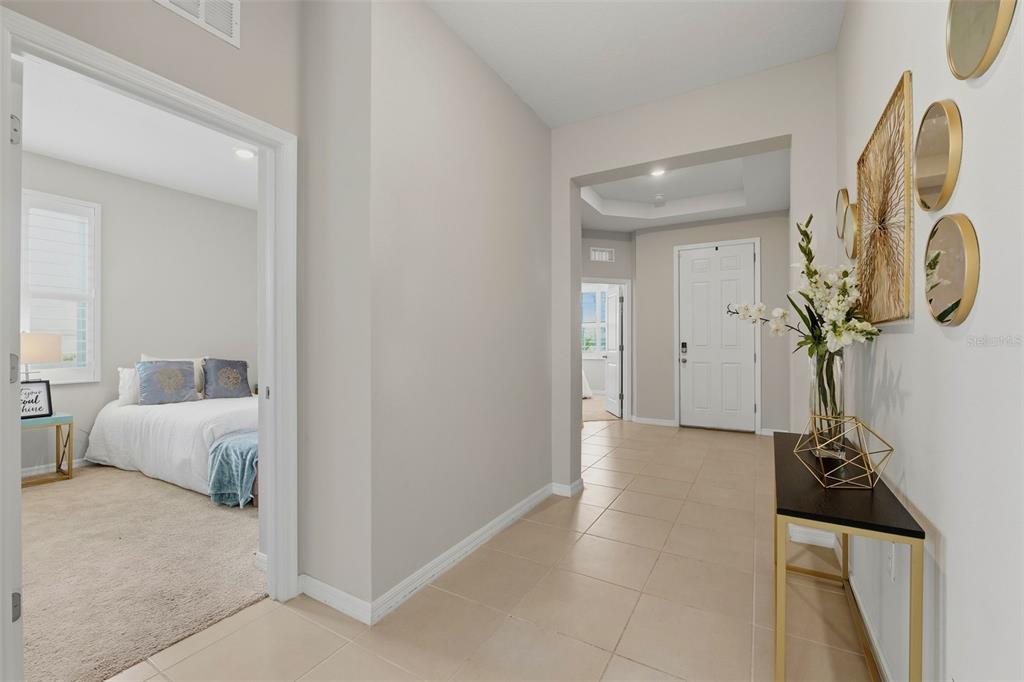 An entryway with beige walls, tile flooring, a tray ceiling, and a white front door — 32337 CONCHSHELL SAIL STREET, WESLEY CHAPEL, FL