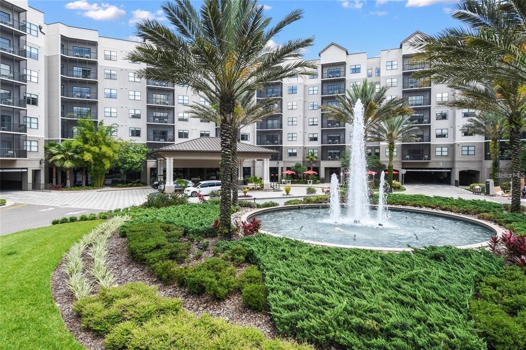 A multi-story apartment building features a circular fountain and palm trees in the front courtyard — 14501 GROVE RESORT AVENUE UNIT 2221, WINTER GARDEN, FL