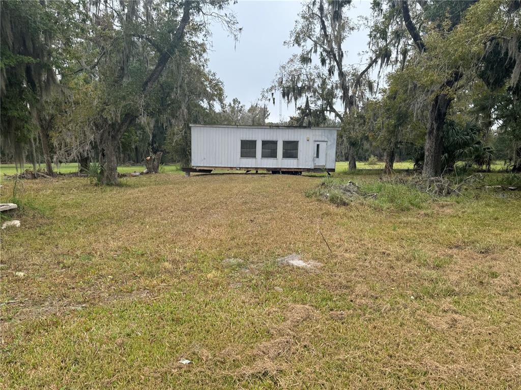A small, rectangular mobile home sits in the middle of a grassy, tree-filled lot — 108 E MARKET ROAD, STARKE, FL