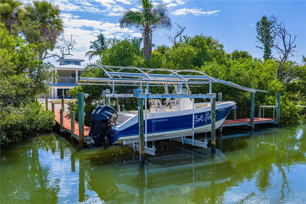 A blue and white motorboat is docked on a lift in a canal near mangroves — 550 N GULF BOULEVARD, PLACIDA, FL