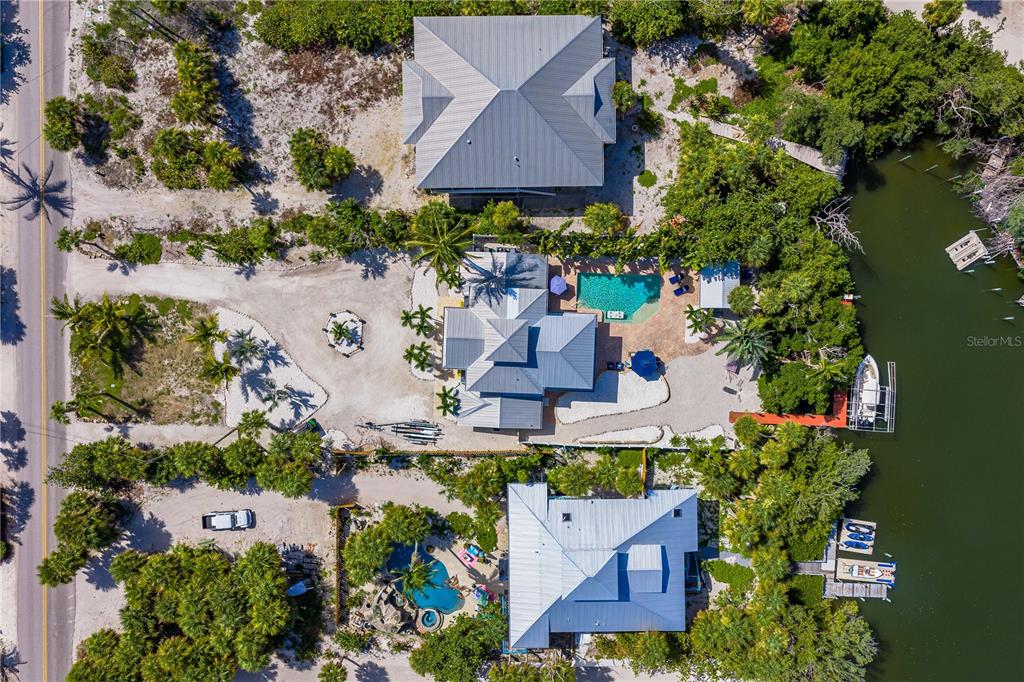 An aerial view shows three waterfront houses with pools, docks, and lush landscaping — 550 N GULF BOULEVARD, PLACIDA, FL