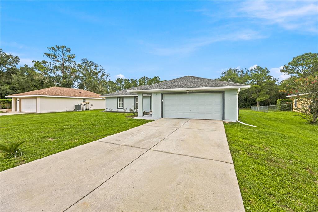 A light green single-story house with a two-car garage and a concrete driveway — 47 REDWOOD TRACK COURSE, OCALA, FL