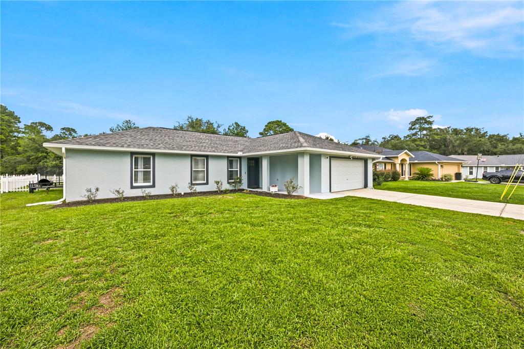 A single-story house with a light blue exterior, a gray roof, and a two-car garage — 47 REDWOOD TRACK COURSE, OCALA, FL