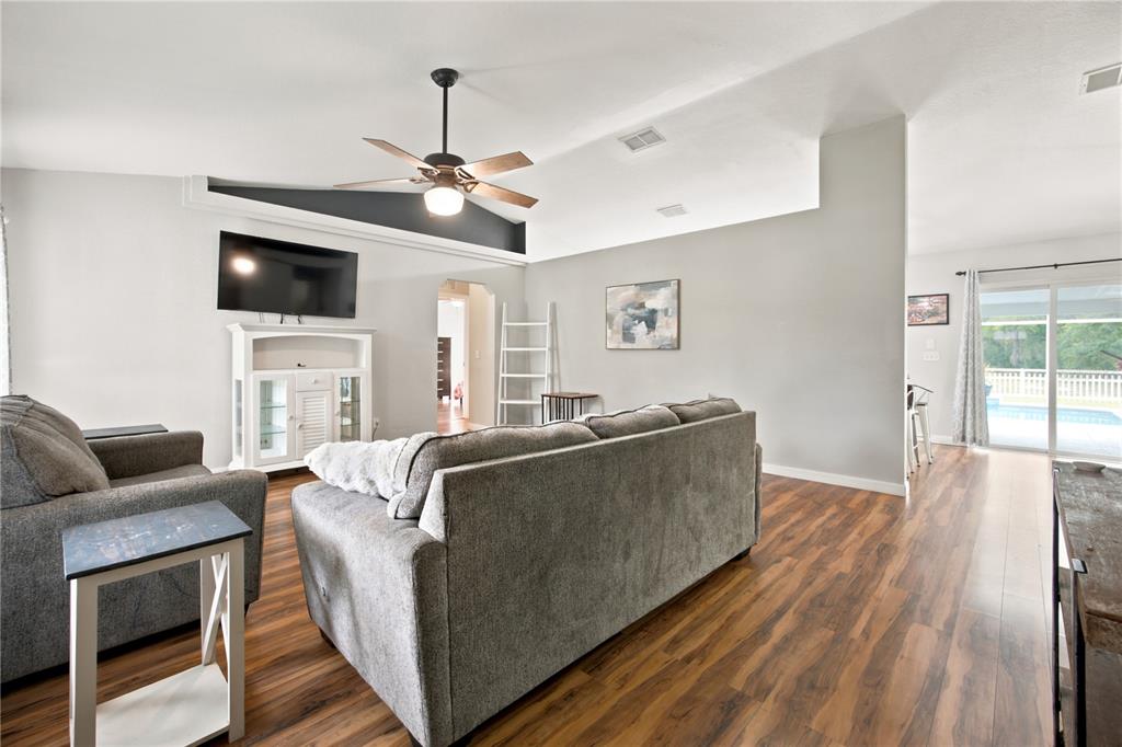 A living room features wood-look flooring, a vaulted ceiling with a fan, and a gray sofa — 47 REDWOOD TRACK COURSE, OCALA, FL