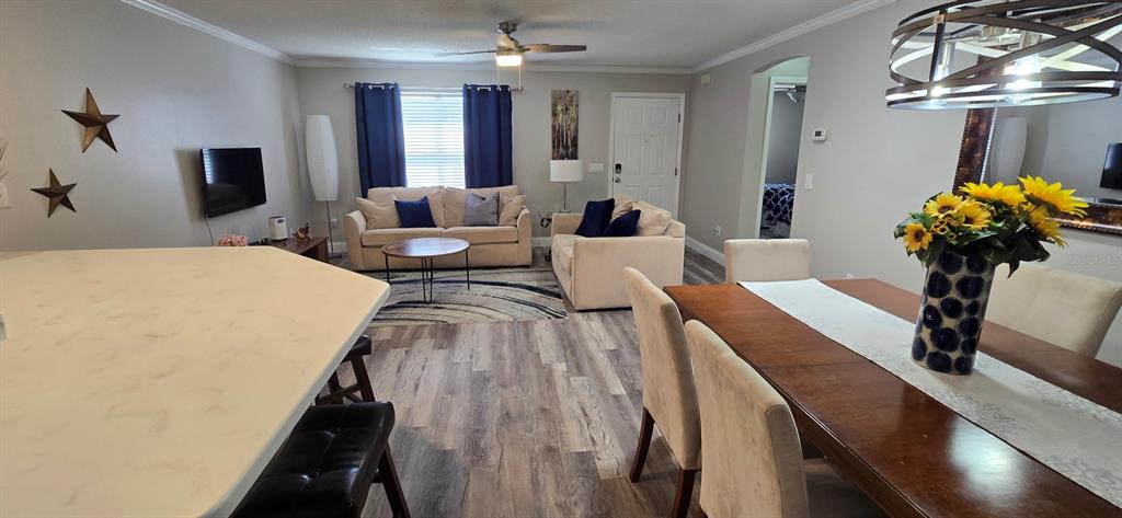 An open-concept living and dining area features light wood-look flooring and neutral furniture — 712 ARTESIA AVENUE, THE VILLAGES, FL