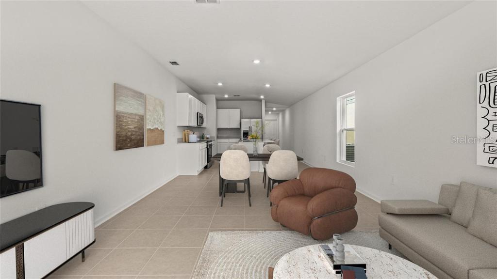 This open-concept living and dining area features tile flooring, white cabinetry, and neutral furniture — 1580 WILLOW GARDEN LOOP, EUSTIS, FL