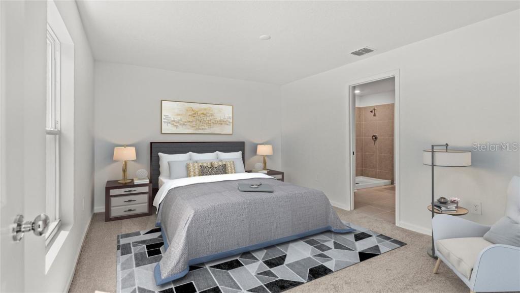 A bedroom features a bed with a geometric rug, two nightstands, and an attached bathroom — 1580 WILLOW GARDEN LOOP, EUSTIS, FL
