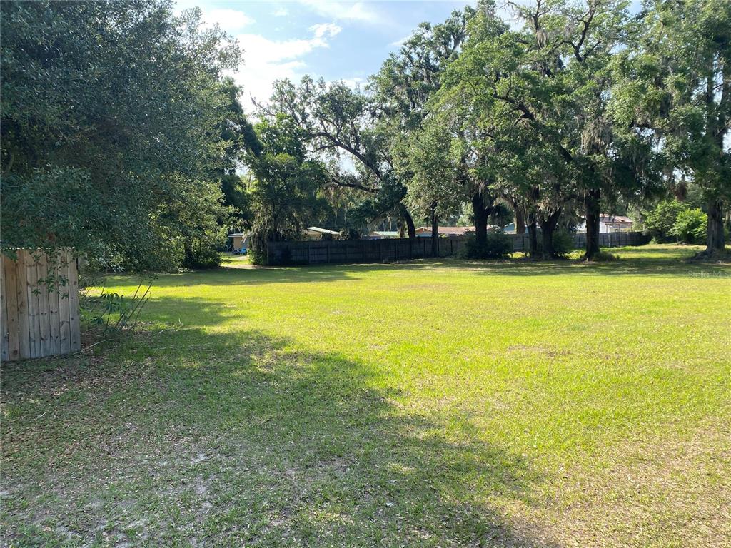 A large, grassy, vacant residential lot features mature trees and a wooden fence — US HWY 301, OXFORD, FL