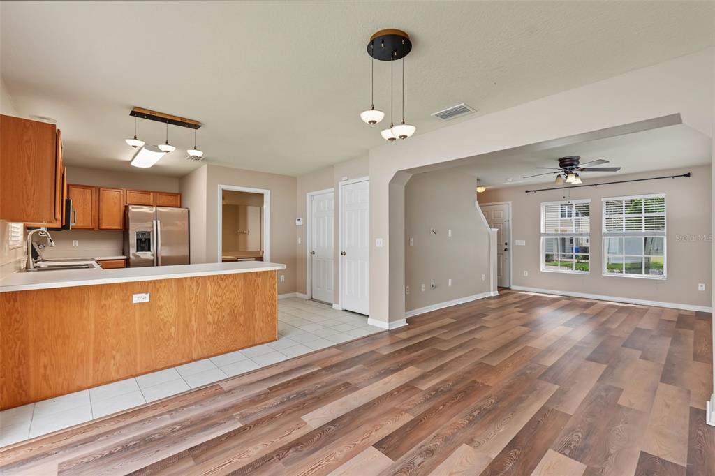 An open-concept kitchen with wood cabinets and a breakfast bar flows into a living area — 150 SAWTOOTH DRIVE, VALRICO, FL