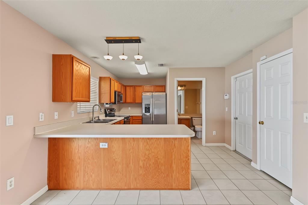A kitchen features wood cabinets, a breakfast bar, stainless steel appliances, and tile flooring — 150 SAWTOOTH DRIVE, VALRICO, FL