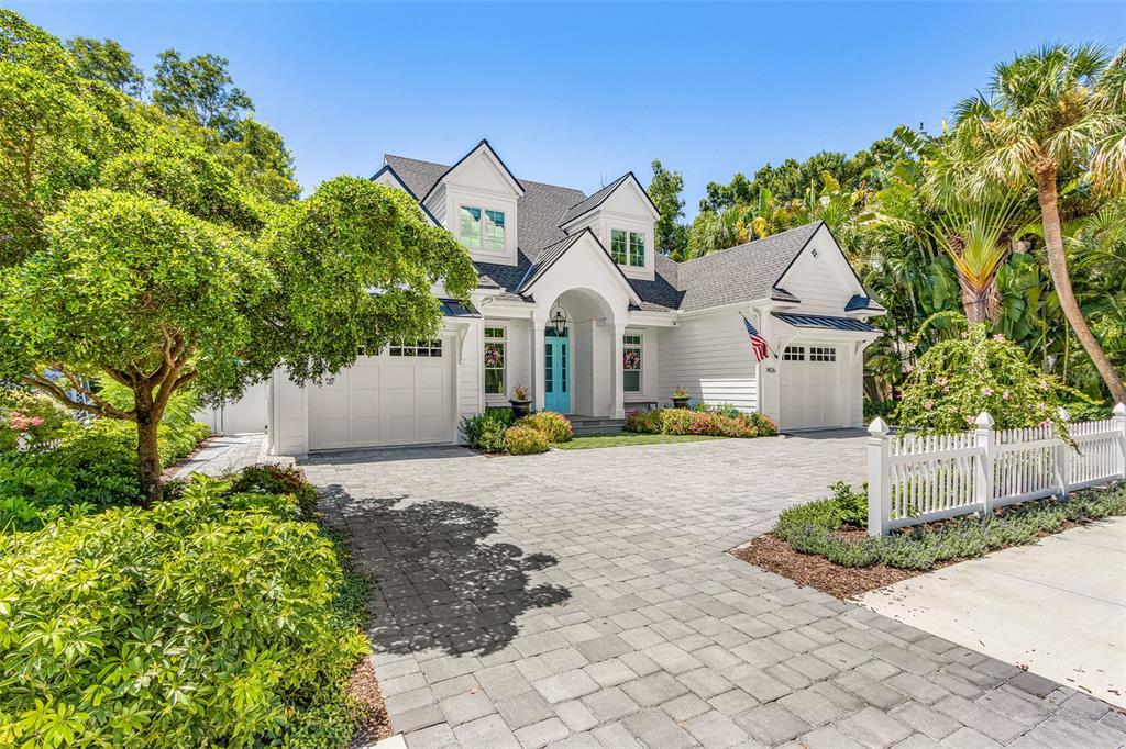 A white two-story house with a paved driveway, blue front door, and lush landscaping — 1426 S OSPREY AVENUE, SARASOTA, FL