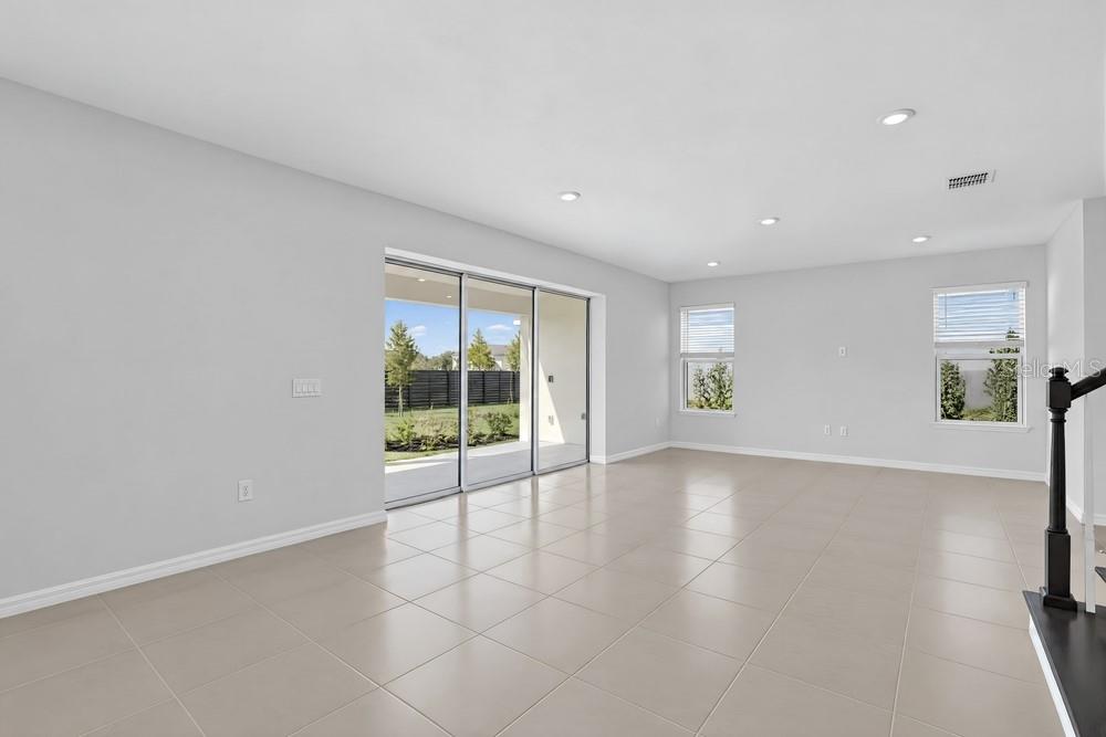A modern white kitchen features a large island, stainless steel appliances, and pendant lighting — 14258 SAWMILL STREET, PARRISH, FL