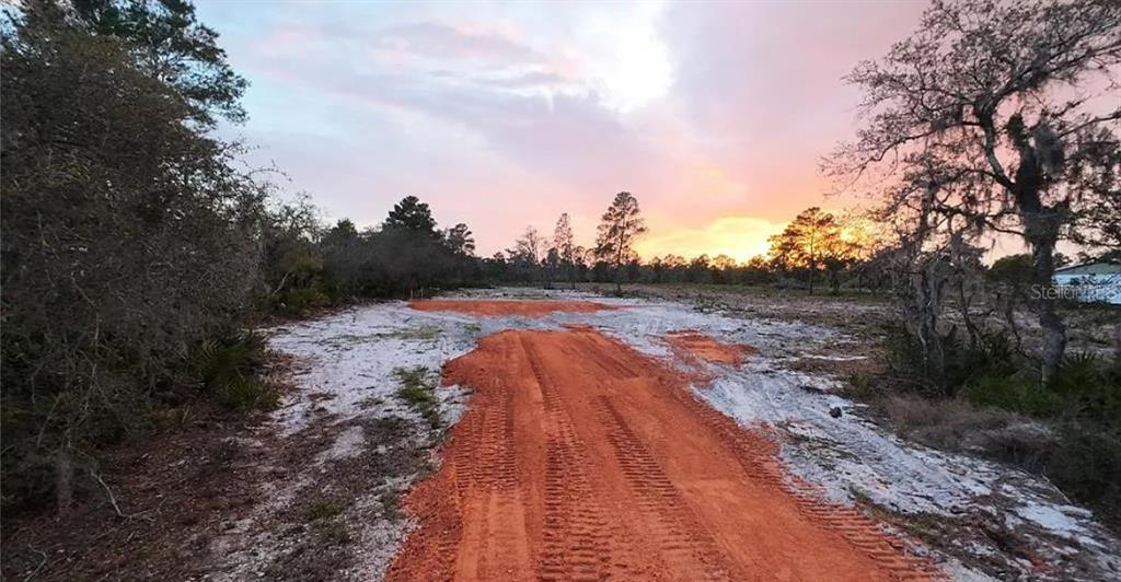 A dirt path leads through a cleared, sandy lot toward a sunset sky — 0 WOODSTORK WAY, FROSTPROOF, FL