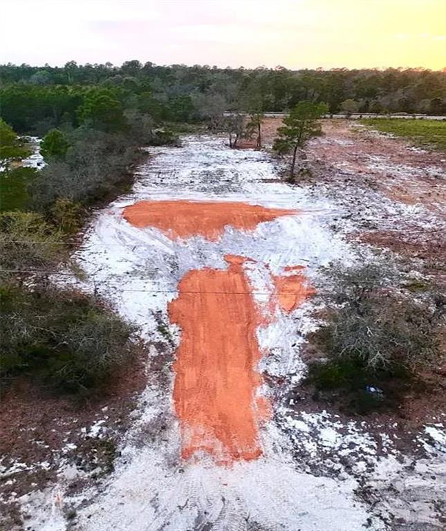 An aerial view shows a cleared, sandy lot with patches of exposed red clay soil — 0 WOODSTORK WAY, FROSTPROOF, FL