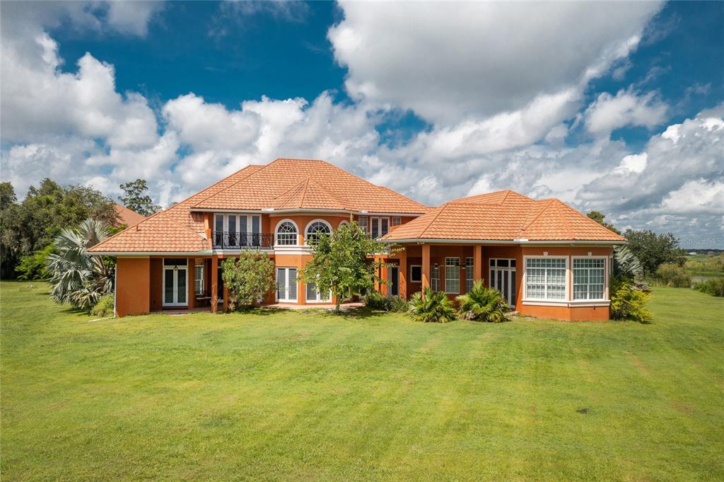 A large two-story orange house with a tiled roof sits on a grassy lawn — 37511 WASHINGTON LOOP ROAD, PUNTA GORDA, FL