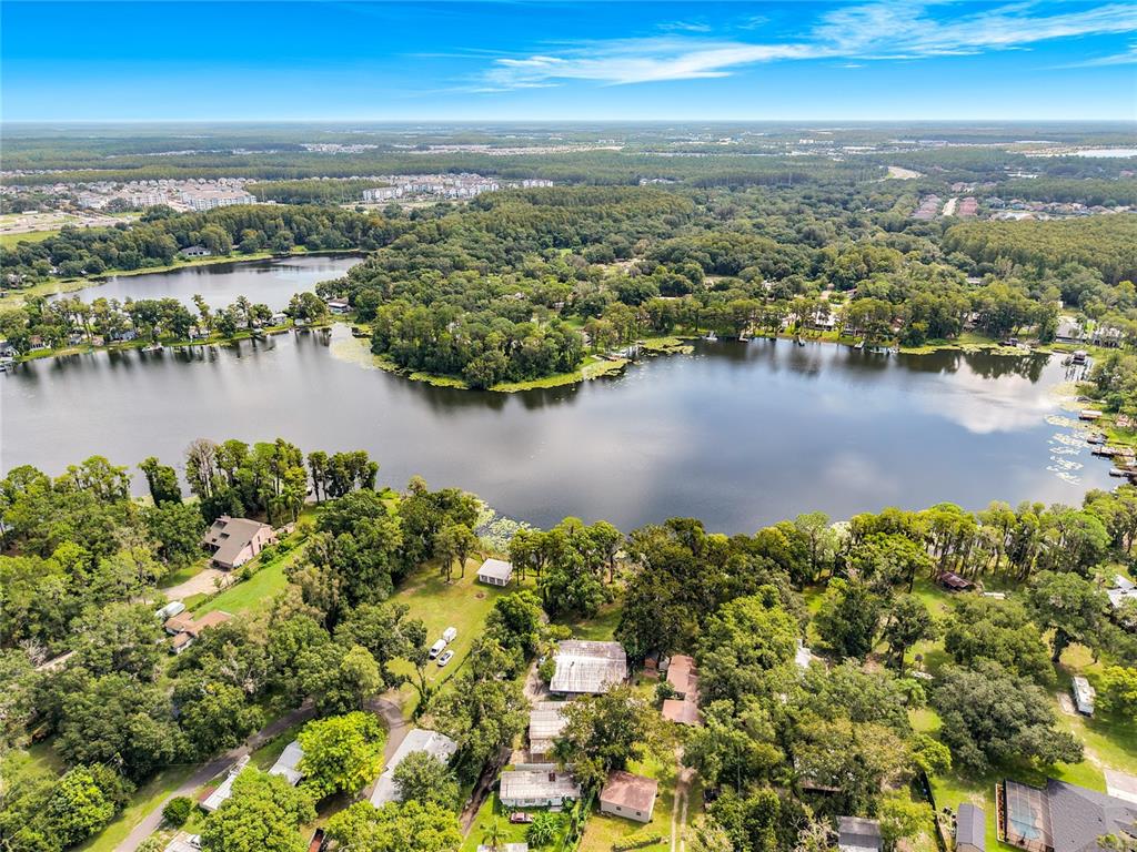 An aerial view shows a lake surrounded by dense trees and several residential properties — 14446 SHANGRILA LANE, ODESSA, FL
