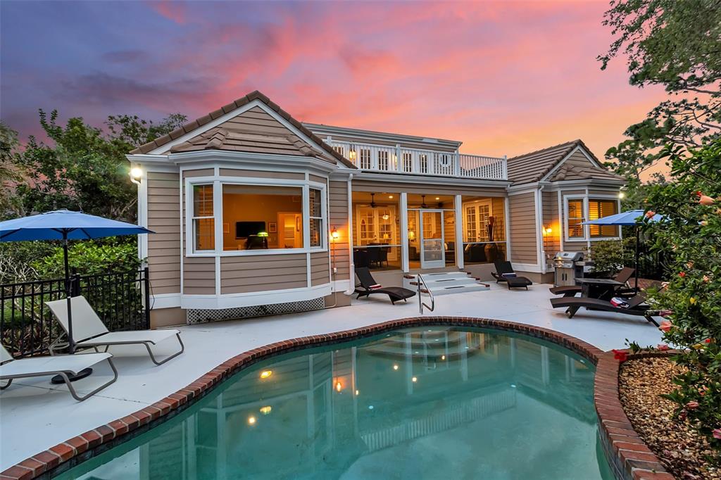 An aerial view of a house with a tiled roof surrounded by dense forest at sunset — 156 BISHOPS COURT ROAD, OSPREY, FL