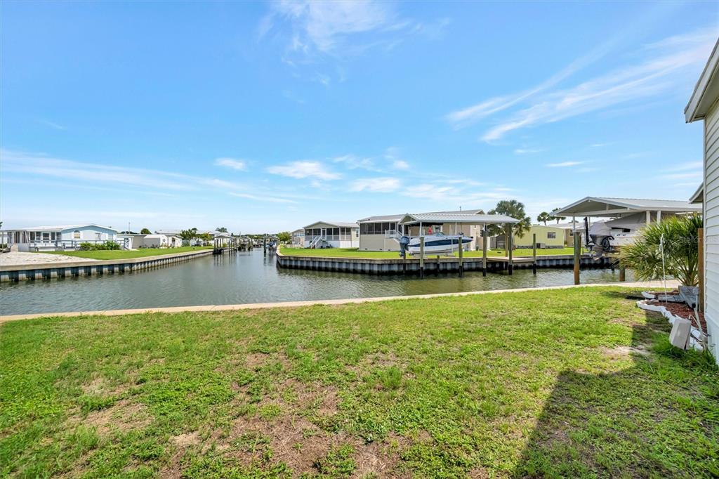 A grassy yard overlooks a canal with boat docks and several waterfront mobile homes — 162 S SAINT THOMAS CIRCLE, APOLLO BEACH, FL