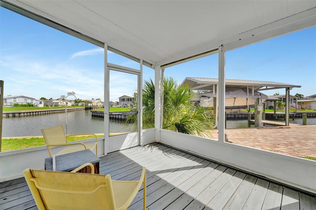 A screened-in porch with wooden flooring overlooks a canal and a boat dock — 162 S SAINT THOMAS CIRCLE, APOLLO BEACH, FL