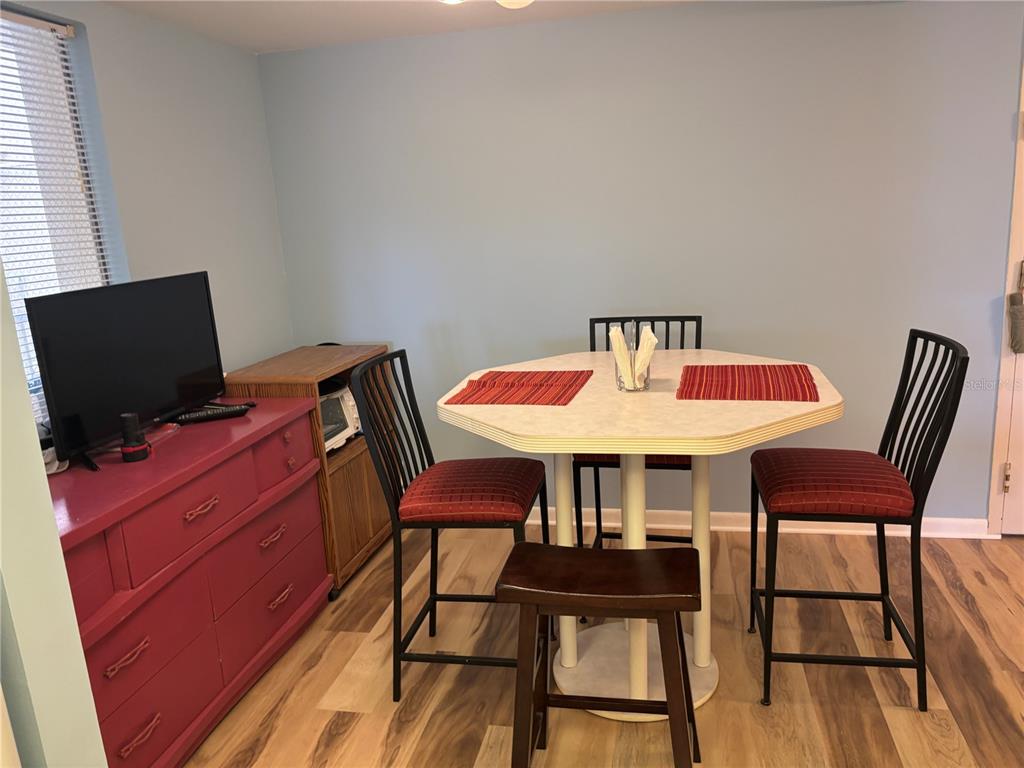 A dining area features a light-colored octagonal table, three chairs, and a red dresser — 4910 38TH WAY S UNIT 411, ST PETERSBURG, FL