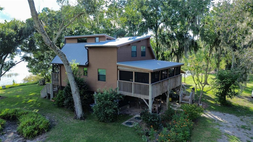 A two-story house with brown siding and a metal roof sits near a lake — 733 N LAKE REEDY BOULEVARD, FROSTPROOF, FL