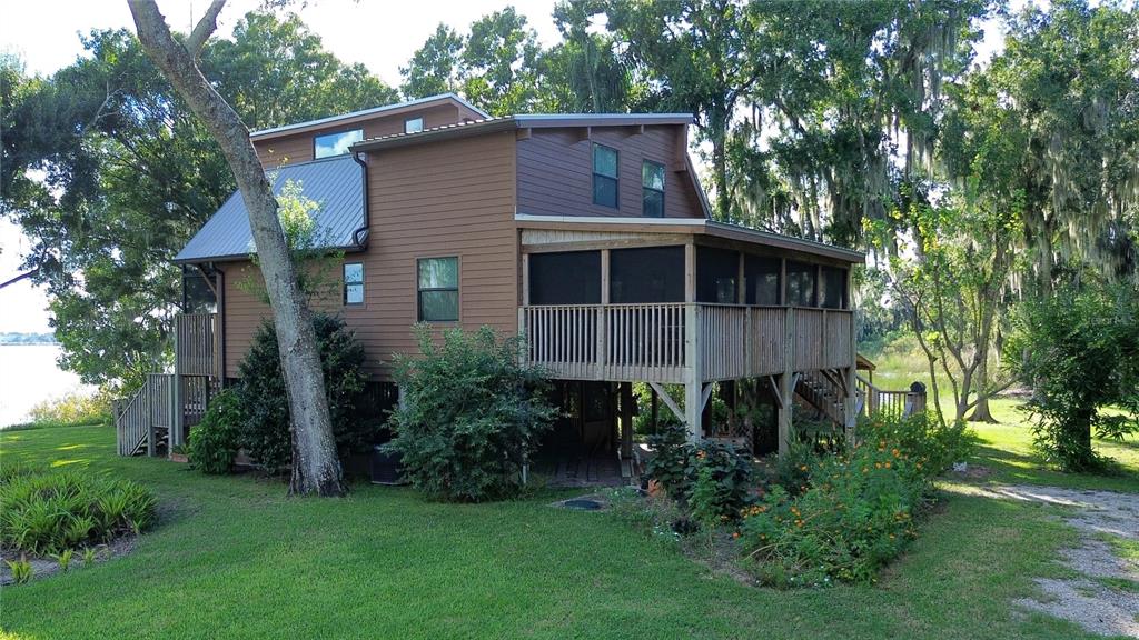 A two-story brown house with a metal roof and a large screened-in wooden deck — 733 N LAKE REEDY BOULEVARD, FROSTPROOF, FL
