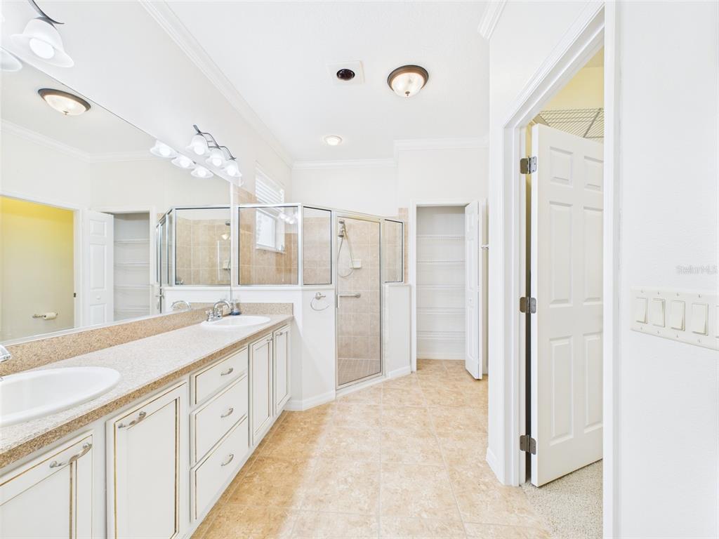 A bathroom features a double vanity, a glass-enclosed shower, and a walk-in closet — 375 SIMPSON STREET, THE VILLAGES, FL